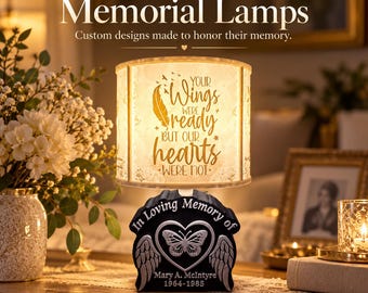 May include: A cylindrical lamp with a light-up shade featuring the text "YOUR Wings WERE ready BUT OUR hearts WERE NOT." The black base displays a silver butterfly, angel wings, and the text "In Loving Memory of MARY A. McINTYRE 1964-1985."