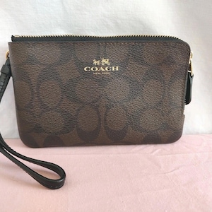 Cartera de muñeca con cremallera en las esquinas dobles de COACH, marrón y negra, con revestimiento exclusivo