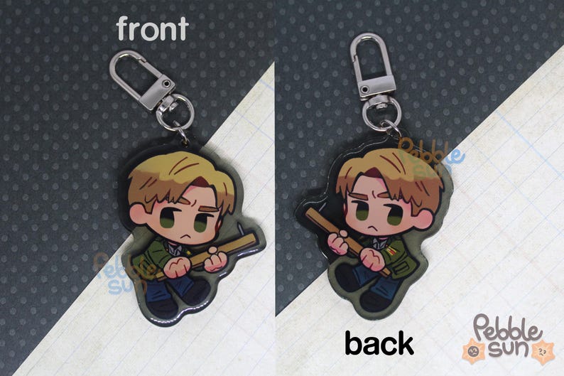 May include: A keychain featuring a cartoon character holding a tool. The front of the keychain shows the character with a light brown hair and a green shirt. The back of the keychain shows the character with a light brown hair and a green shirt. The keychain is made of acrylic.