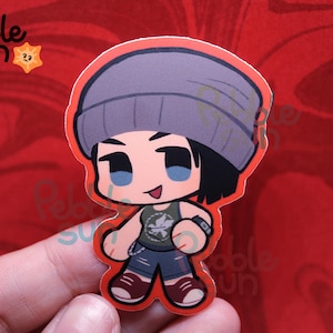 May include: A sticker featuring a cartoon character with a gray beanie, black hair, and blue eyes. The character wears a green tank top, blue shorts, and maroon shoes. The sticker has a red border and the text "Pebble Sun" is in the upper left corner.