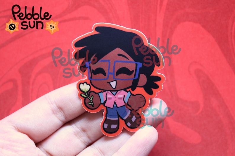 May include: A sticker featuring a cartoon character with dark skin, black hair, and blue glasses, holding a white flower. The character wears a pink vest, blue jeans, and brown sandals. The sticker has the text "Pebble Sun" and a sun logo.