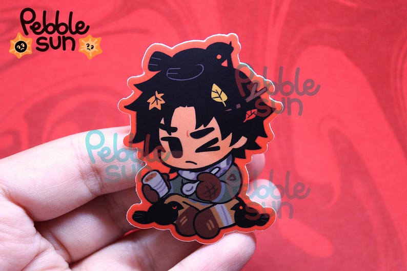 May include: A sticker featuring a cartoon character with black hair adorned with autumn leaves. The character is wearing a scarf and holding a cup. The sticker has a red outline and the words "Pebble Sun" are visible.
