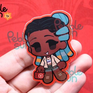 May include: A sticker featuring a cartoon character with dark skin, black hair, and blue highlights. The character wears a white jacket, shorts, and brown boots, holding a red first aid kit. The sticker has a red border and the text "Pebble Sun".