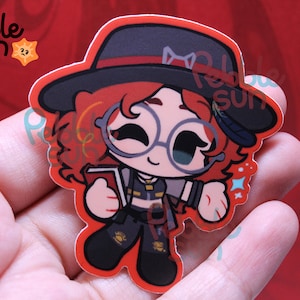 May include: A sticker featuring a cartoon character with red curly hair, round glasses, and a black hat. The character is holding a book and wearing a dark outfit. The sticker has a red border and the text "Pebble Sun" is visible.