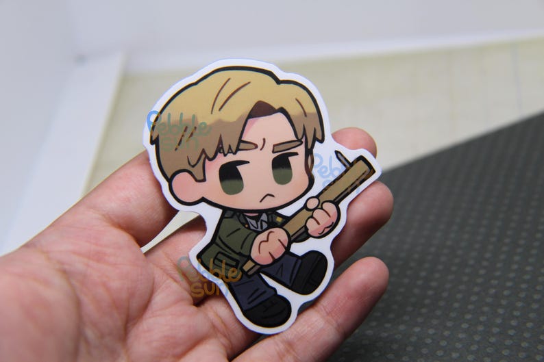 May include: A sticker featuring a cartoon character with blonde hair, wearing a green jacket and black pants, holding a wooden weapon. The character has a serious expression and is outlined in black.