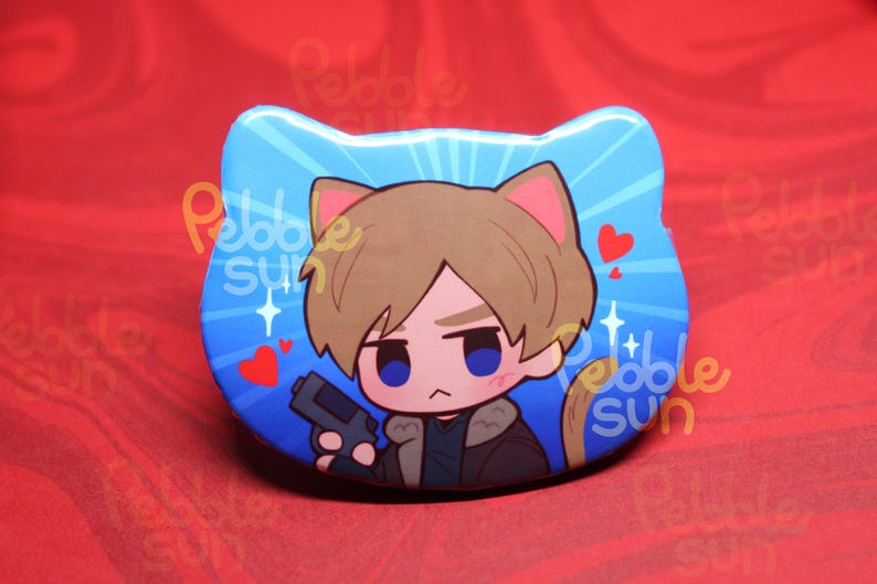 May include: A blue, cat-shaped button featuring a cartoon character with brown hair, holding a gun. The background is blue with white sparkles and red hearts. The button has the text "Pebble Sun".