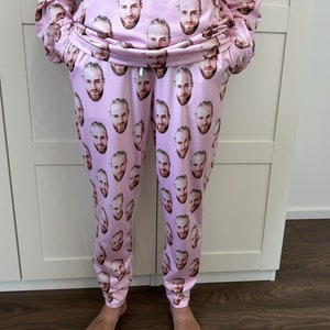 May include: Pink sweatpants with a repeated pattern of a man's face.