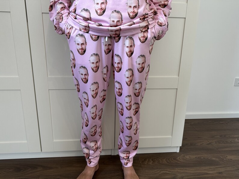 May include: Pink sweatpants with a repeated pattern of a man's face.