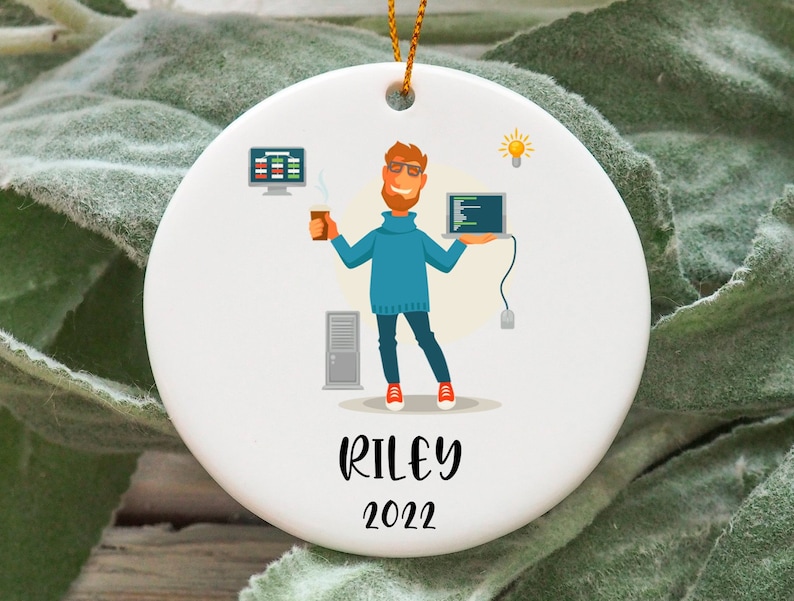 May include: White ceramic ornament with a cartoon illustration of a person holding a laptop and a cup of coffee. The ornament has the text "RILEY 2022" on the bottom.