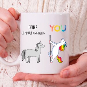 May include: White ceramic mug with a humorous design featuring two unicorns. The text on the mug reads "Other Computer Engineers" and "You". The unicorn representing "You" is a rainbow unicorn with a rainbow mane and tail, while the other unicorn is gray.