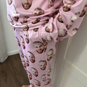 May include: Pink pajamas with a repeating pattern of a man's face.