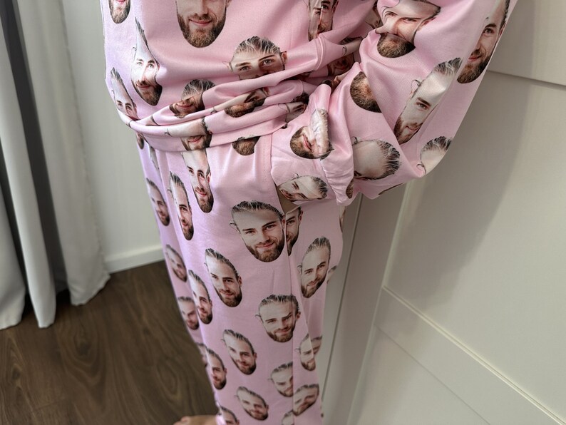 May include: Pink pajamas with a repeating pattern of a man's face.