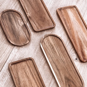 Puede incluir: Cinco bandejas de servir de madera en varias formas y tamaños. Las bandejas están hechas de madera natural de color marrón claro. Las bandejas son perfectas para servir aperitivos, entremeses o postres.