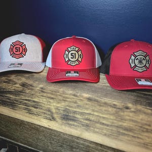 May include: A white ceramic mug with a black handle and the text "But First, Coffee" in a bold, black font. The mug is filled with a dark liquid, likely coffee, and sits on a light-colored surface.