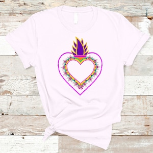 May include: A white t-shirt with a purple, yellow, and green heart design. The heart is surrounded by a wreath of flowers and has a flame on top.