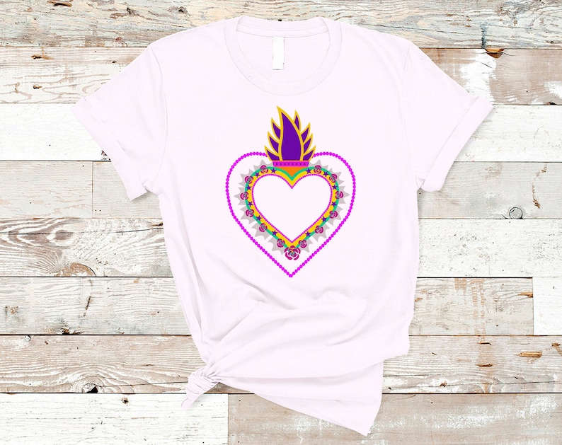 May include: A white t-shirt with a purple, yellow, and green heart design. The heart is surrounded by a wreath of flowers and has a flame on top.