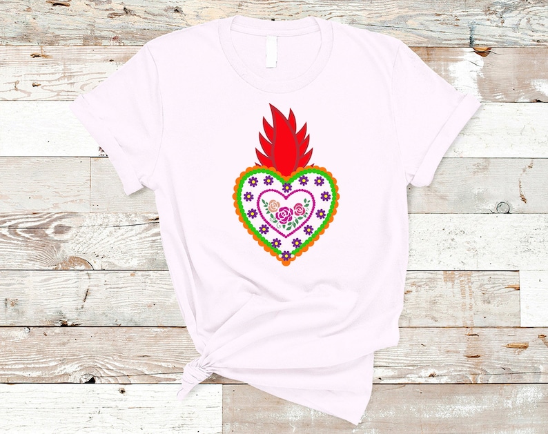 May include: White t-shirt with a red, orange, green, purple, and pink embroidered heart with flowers. The heart is a traditional Mexican folk art design.