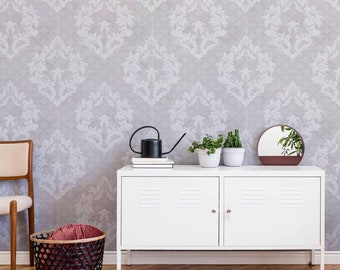 May include: A white cabinet with two doors and a gray patterned wallpaper behind it. There are two potted plants and a watering can on top of the cabinet. A round mirror with a brown frame is on the wall.
