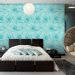 May include: A bedroom with a teal blue wall featuring a seashell pattern wallpaper. A bed with a white duvet and blue throw pillows is in the center of the room. A hanging wicker chair is in the corner of the room.