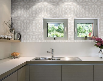 May include: A modern kitchen with a double sink, gray cabinets, and a tiled backsplash with a geometric pattern. Two windows with views of greenery are above the sink.