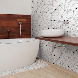 May include: A white bathtub with a white porcelain sink on a wooden countertop. The wall behind the sink is covered in a geometric black and white wallpaper.