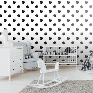 May include: A white nursery with black polka dot wallpaper. A white crib with a white rocking horse and a white dresser are in the room.