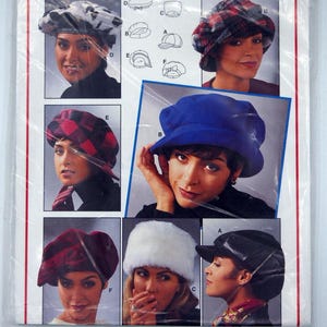 May include: A Burda pattern packet featuring various hat designs. The packet includes images of women wearing different styles of hats, including a blue cloche, a plaid beret, and a white fur hat. The packet also includes measurements in inches and centimeters.