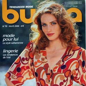 May include: Magazine cover with a woman with red hair and blue eyes. She wears a patterned top in orange, red, and brown tones. The magazine title is "bu" with "TENDANCES MODE" above. The cover also features the text "Belles perspectives".