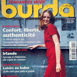 May include: A vintage magazine cover featuring a woman in a red dress holding a matching handbag. The magazine title is "Burda" with text in French. The cover includes the text "Tendances Mode" and "Cadeaux de saison".