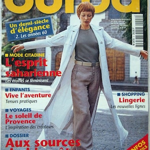 May include: A magazine cover featuring a woman wearing a white coat and khaki trousers. The magazine is titled "Burda" and the cover text reads "Un demi-siècle d'élégance 2. Les années 60".