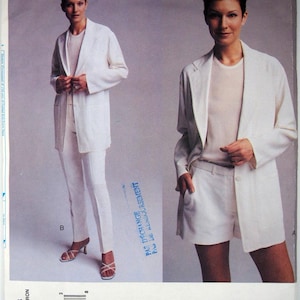 Pode incluir: Um blazer branco com uma blusa branca e calças brancas. O blazer tem um estilo longo e fluido e um fecho de um único botão. As calças são ajustadas e têm uma perna direita. A blusa é um design simples e sem mangas. A modelo está usando o look com uma pose confiante e elegante.