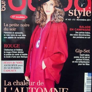 Peut inclure: Une couverture de magazine mettant en scène une femme portant un manteau rouge et un chapeau noir. Le magazine est intitulé "Burda Style" et le texte de la couverture est "La chaleur de L'AUTOMNE" et "De la couleur et du style pour égayer l'humeur de la froide saison".