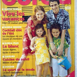 May include: A magazine cover featuring a family of four, a woman, a man, and two children, all wearing summery clothing. The magazine is titled "Burda" and the cover text reads "Vive les vacances" and "Plus de 50 modeles".