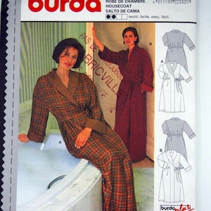 May include: A Burda 2990 sewing pattern envelope for a housecoat. The front shows two variations: a plaid robe with a contrasting collar and cuffs, and a solid dark red robe. Includes technical line drawings and size charts.