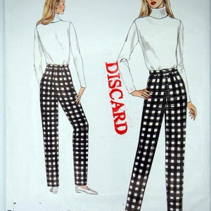 Puede incluir: Patrón de costura Vogue Patterns con ilustraciones de una mujer con un cuello alto blanco y pantalones a cuadros blancos y negros. La palabra "DISCARD" está impresa en rojo. Impreso en EE. UU.