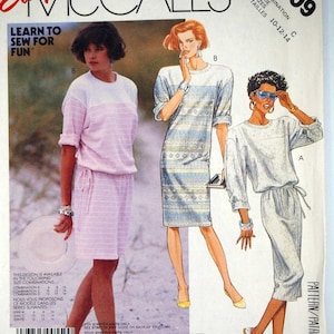 May include: A McCall's 2909 sewing pattern envelope featuring illustrations of three different dress styles. The designs include a light pink two-piece look, a blue and white patterned shift dress, and a solid light-coloured dress with a drawstring waist.