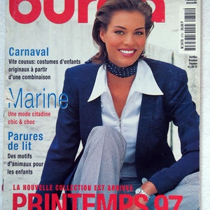 May include: A magazine cover featuring a woman in a navy blazer and patterned pants. The cover has the title "burda" in large red letters, with the text "PRINTEMPS 97" in red. Additional text includes "L'UNIVERS DE LA MODE" and "Marine".