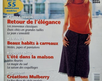 May include: A magazine cover featuring a woman wearing a red turtleneck sweater and a black skirt. The magazine is titled "Burda" and the cover text reads "Retour de l'élégance" and "L'été dans la maison".
