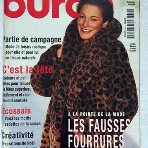 Peut inclure: Une couverture de magazine vintage avec une femme portant un manteau en fausse fourrure à imprimé léopard. Le titre du magazine est "L'UNIVERS DE LA MODE" avec le mot "burda" en grandes lettres rouges. Le titre "LES FAUSSES FOURRURES" est également visible.