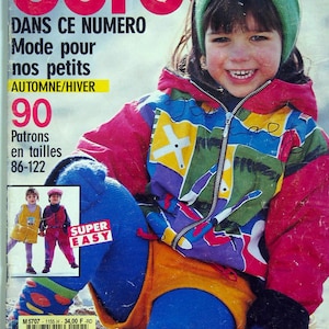 May include: A magazine cover featuring a smiling child wearing a colorful jacket, blue tights, and an orange skirt. The cover has the text "SPECIAL burda" in large red letters, with additional text in French. A smaller image shows two children in outfits.