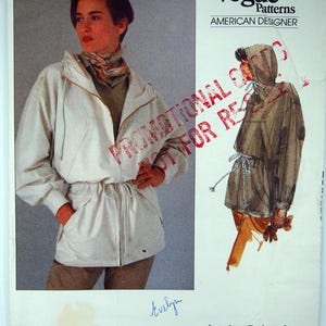 May include: Vogue Patterns sewing pattern with a Calvin Klein design. The cover displays a woman in a white jacket and a sketch of a hooded jacket. The text includes "PROMOTIONAL" and "AMERICAN DESIGNER". Pattern 2461.
