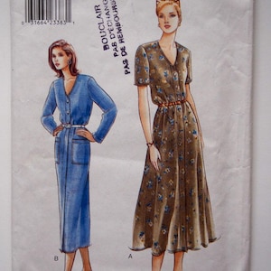 Pode incluir: Um envelope de padrão Very Easy Very Vogue. O envelope apresenta ilustrações de dois vestidos. Um é um vestido azul de manga comprida com cinto, e o outro é um vestido castanho de manga curta com padrão floral. O número do padrão é 9451.