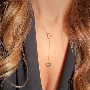 Puede incluir: Un collar de oro con un colgante en forma de corazón. El colgante tiene una pequeña letra 'F' grabada.