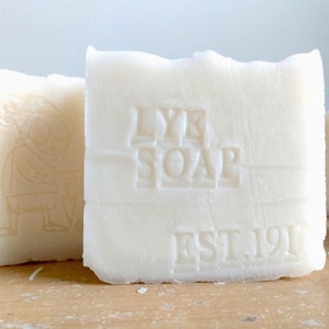 Pu&ograve; includere: Una saponetta bianca di liscivia con le parole "Lye Soap" e "Est. 1912" in rilievo sul davanti.