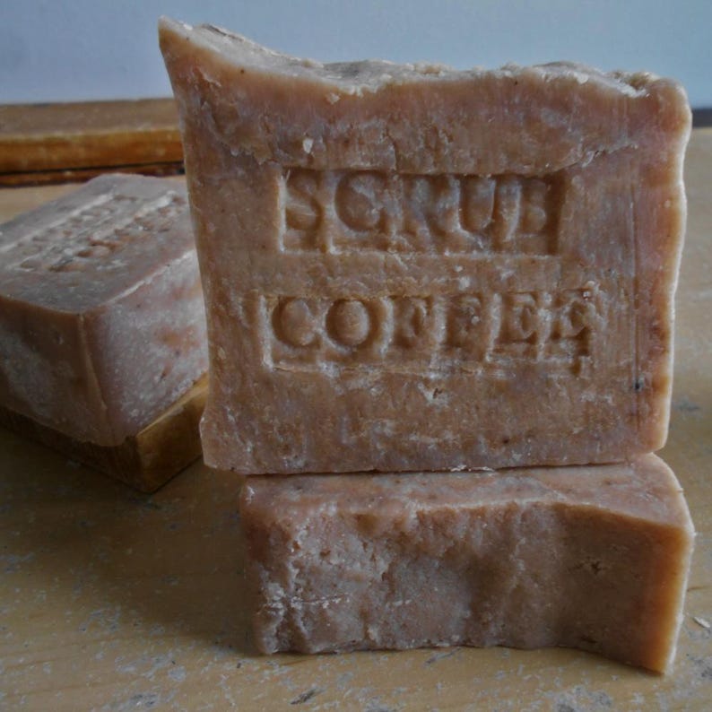 Puede incluir: Tres barras de jab&oacute;n marr&oacute;n apiladas una encima de la otra. La barra superior tiene las palabras "Scrub Coffee" en relieve.