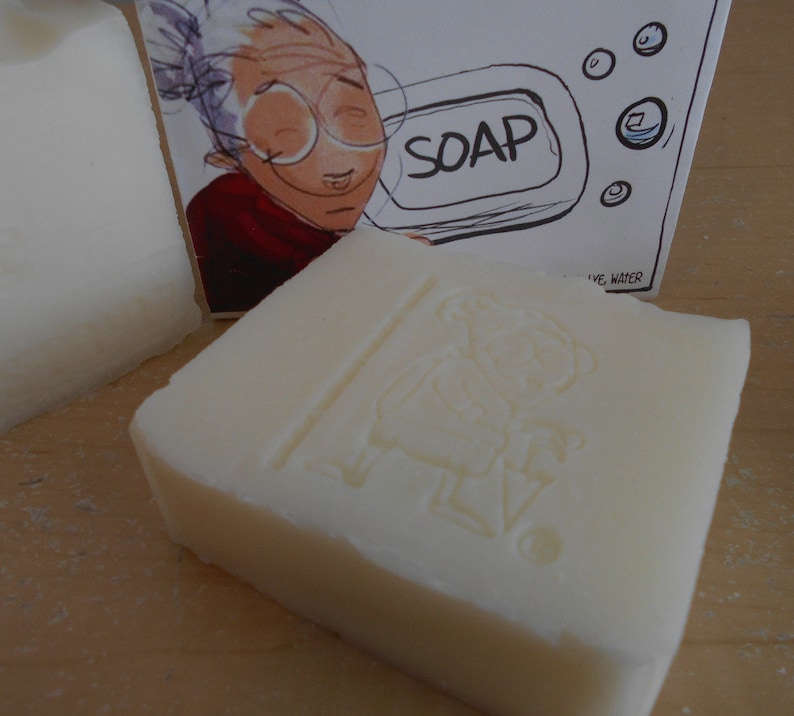 Pu&ograve; includere: Due saponette bianche con un'immagine di cartone animato di una donna con gli occhiali e la parola "SOAP" stampata sulla confezione.