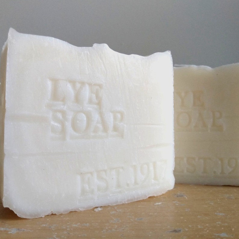 Pu&ograve; includere: Due saponette bianche di liscivia con il testo "LYE SOAP EST 1917" in rilievo sul davanti.