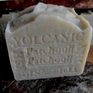 Puede incluir: Una barra de jabón blanca con las palabras "VOLCANIC" y "Patchouli" en relieve.