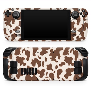 May include: A handheld gaming console with a cow print design. The console features a black screen, buttons, and joysticks. The cow print pattern is brown and white. The back of the console also has the same cow print design.