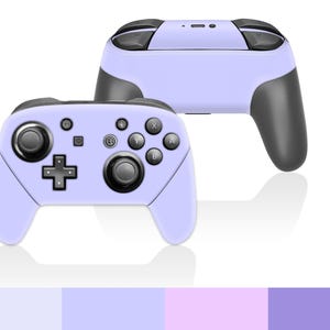 Pode incluir: Dois comandos de jogos sem fios em lilás claro com detalhes em preto. Os comandos têm um design simétrico com botões, joysticks e um direcional. Os comandos são projetados para jogos.